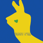 Pocztówka ZAiKS w kolorach Ukrainy. Na niebieskim tle w graficzny sposób przedstawiona dłoń z dwoma palcami w geście zwycięstwa. dłoń jednocześnie przypomina kształtem głowę zająca z zielonym okiem w kształcie serca. Na dloni niebieski napis w dwóch językach, polskim i ukraińskim: „Zwycięstwa i pokoju”